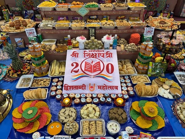 Close view of the Shikshapatri 200 sign surrounded by sweets, cupcakes and colorful papad